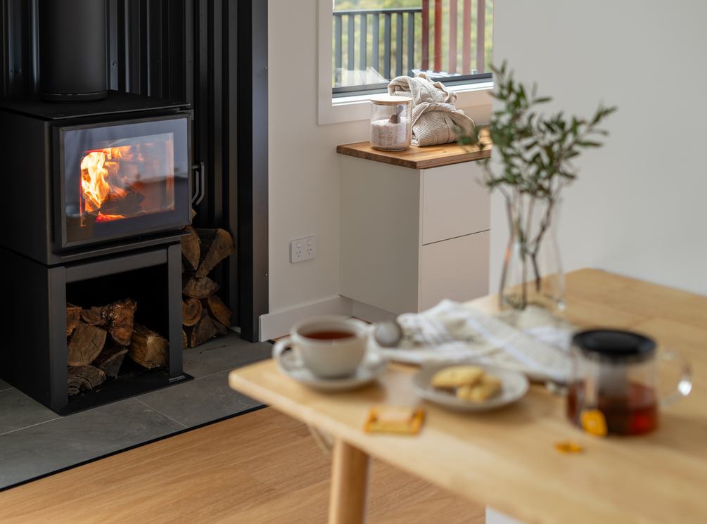 Wood fire burning beside a table set with tea inside a Breath cabin.