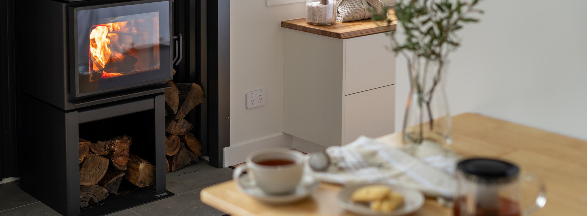 Wood fire burning beside a table set with tea inside a Breath cabin.