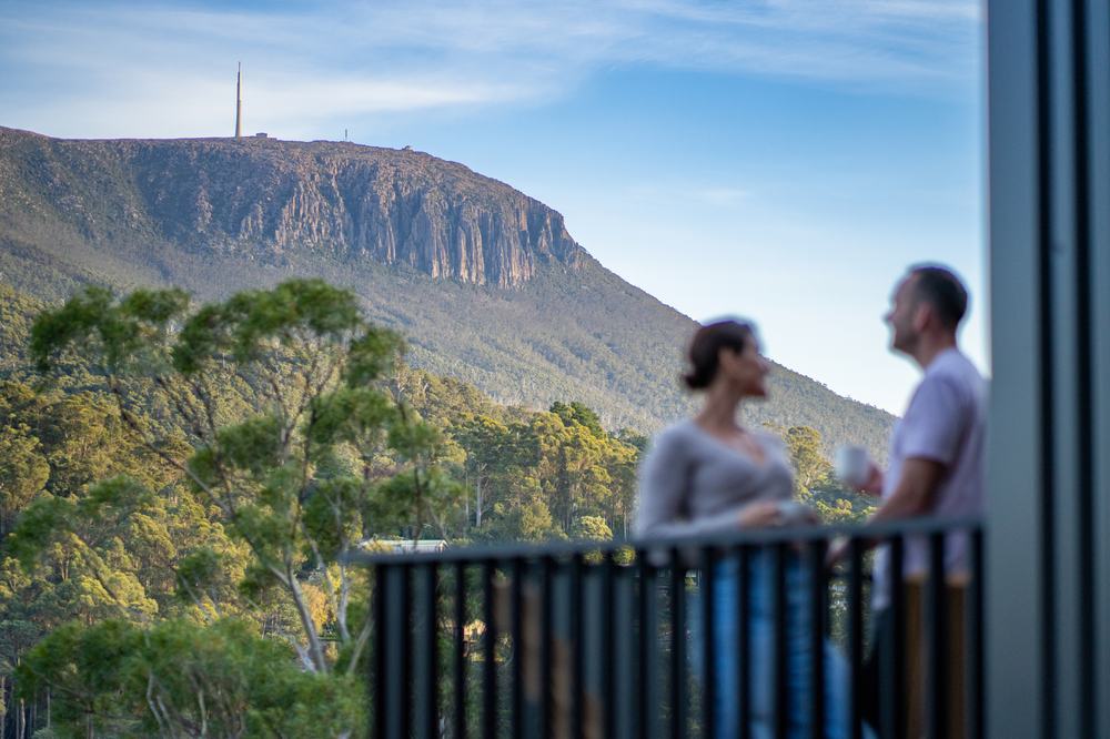 Couple enjoying the view of kunanyi/Mount Wellington from a Breath cabin balcony.