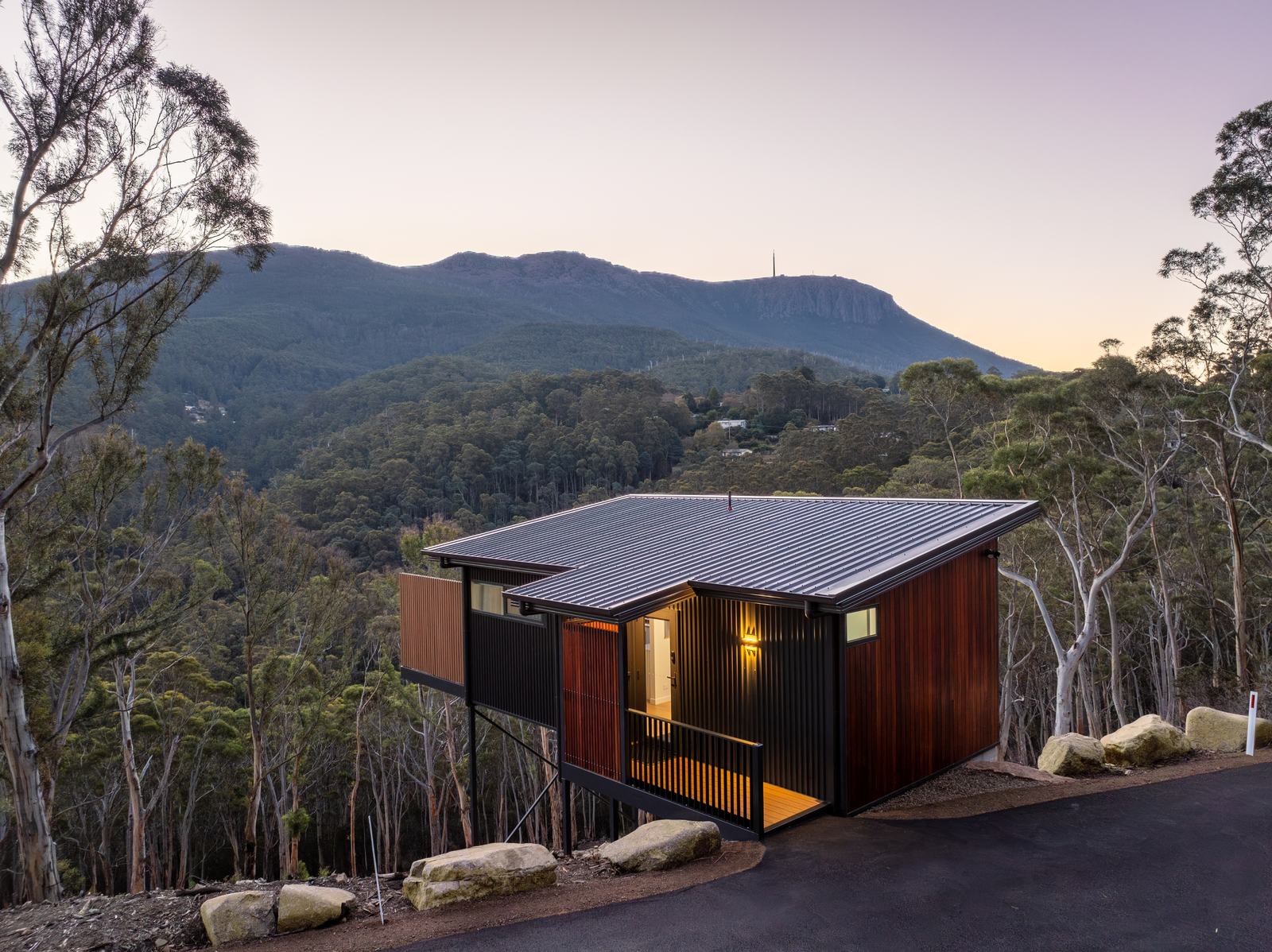 Breath cabin overlooking the forested slopes of kunanyi/Mount Wellington at dusk.