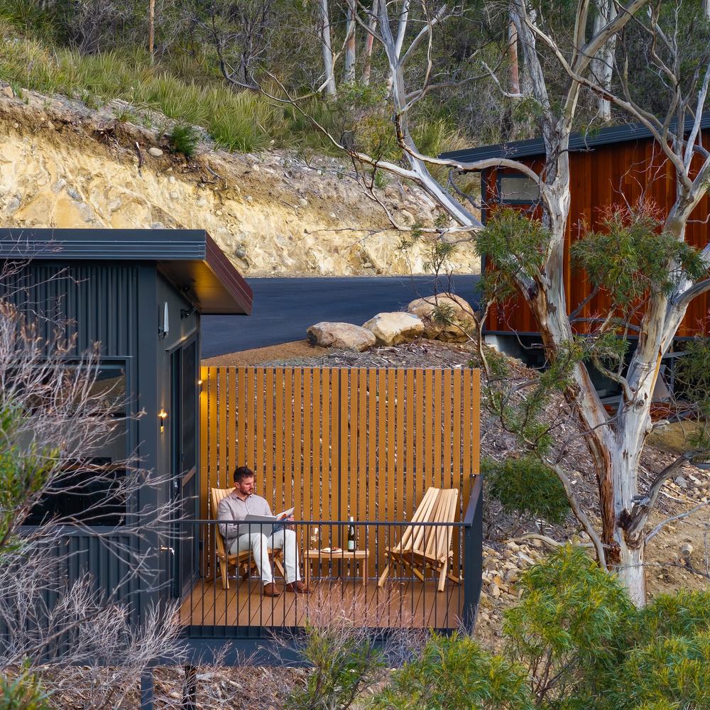 Person sitting on deck amongst gumtrees overlooking the forest