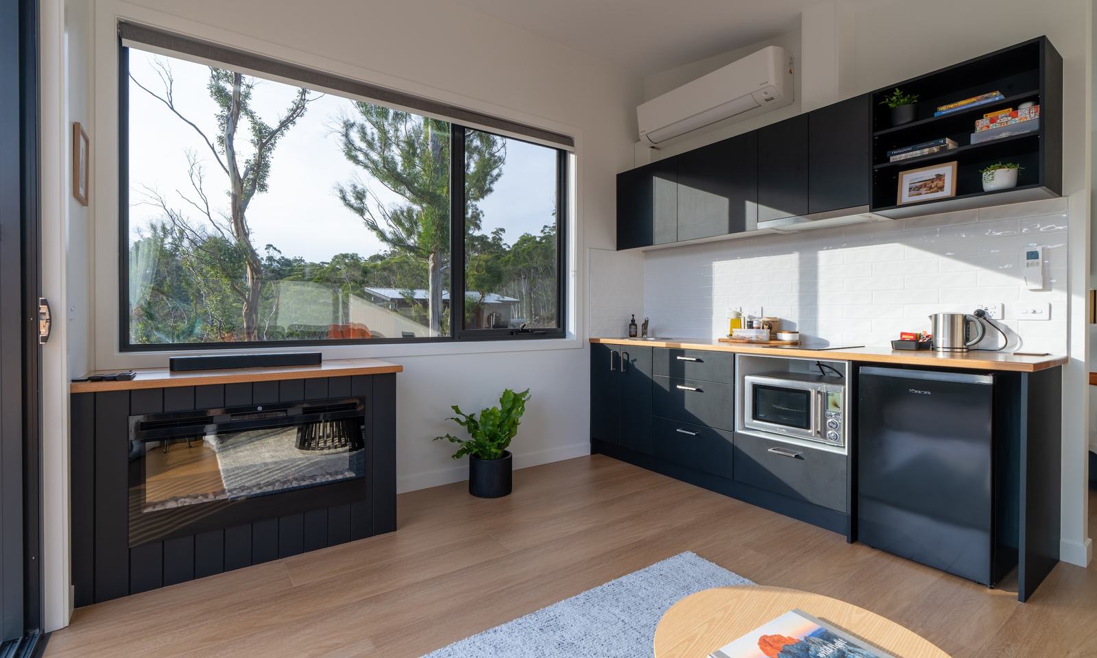 Living room of ironbark cabin with electric fireplace and kitchen