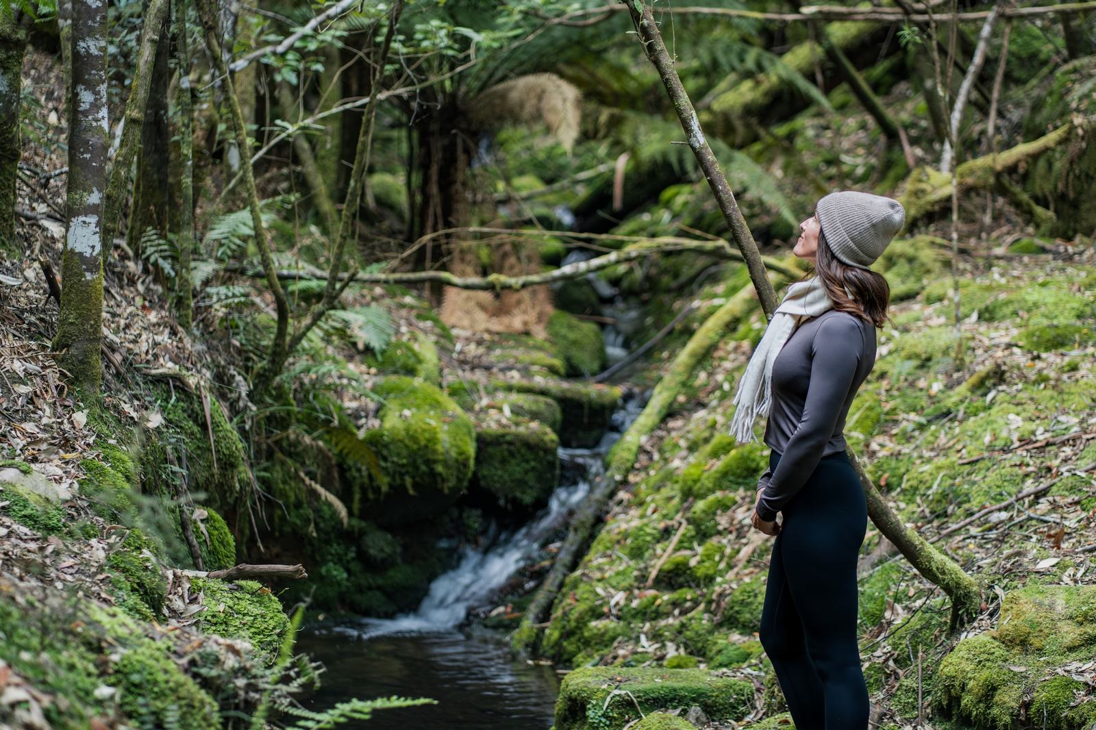 Person standing beside creek with moss and ferns