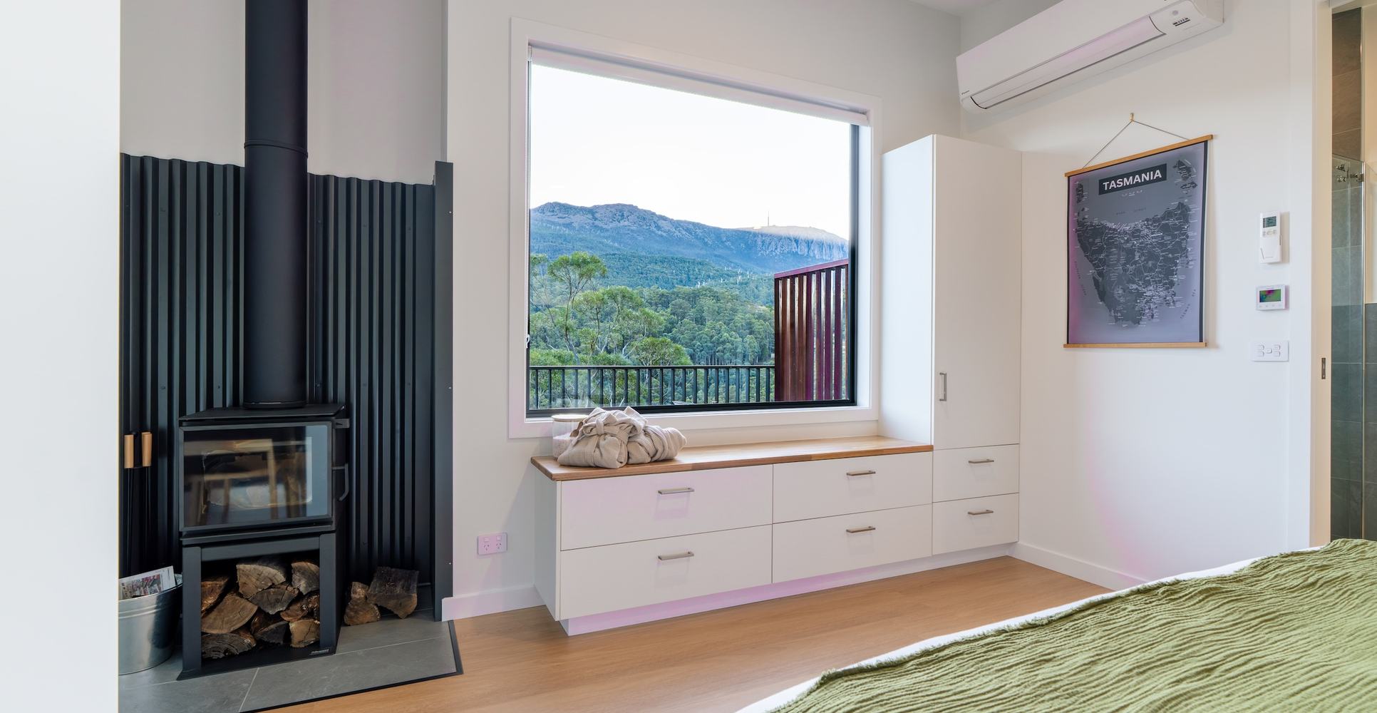 Bedroom with fireplace looking out of large window to forest and mountain