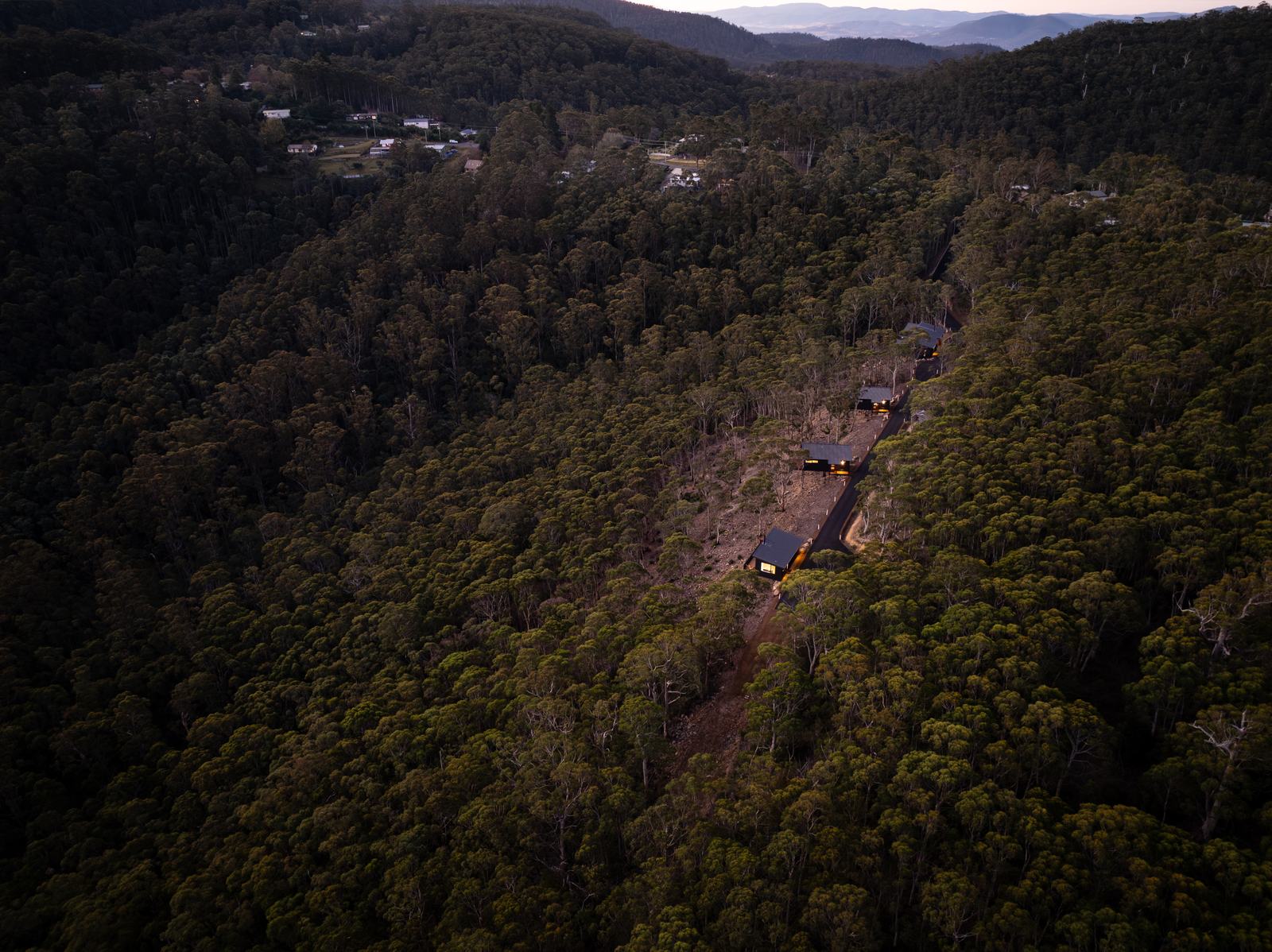 Aerial view of the Breath cabins nestled among the forested hills of Fern Tree, Tasmania.